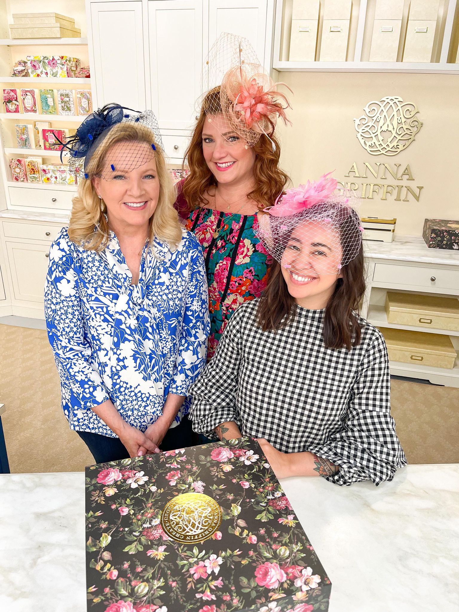 three women standing next to each other in front of a cake.