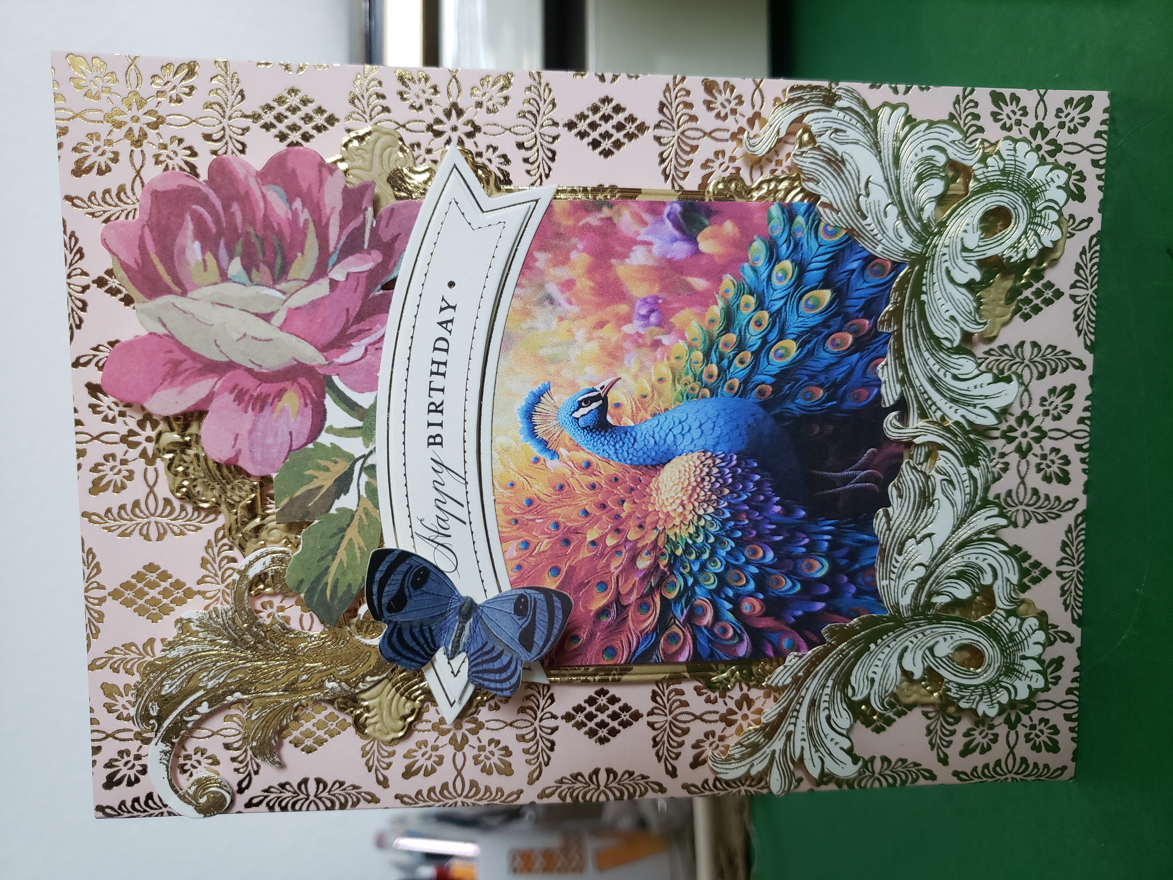 a card with a peacock and flowers on it.