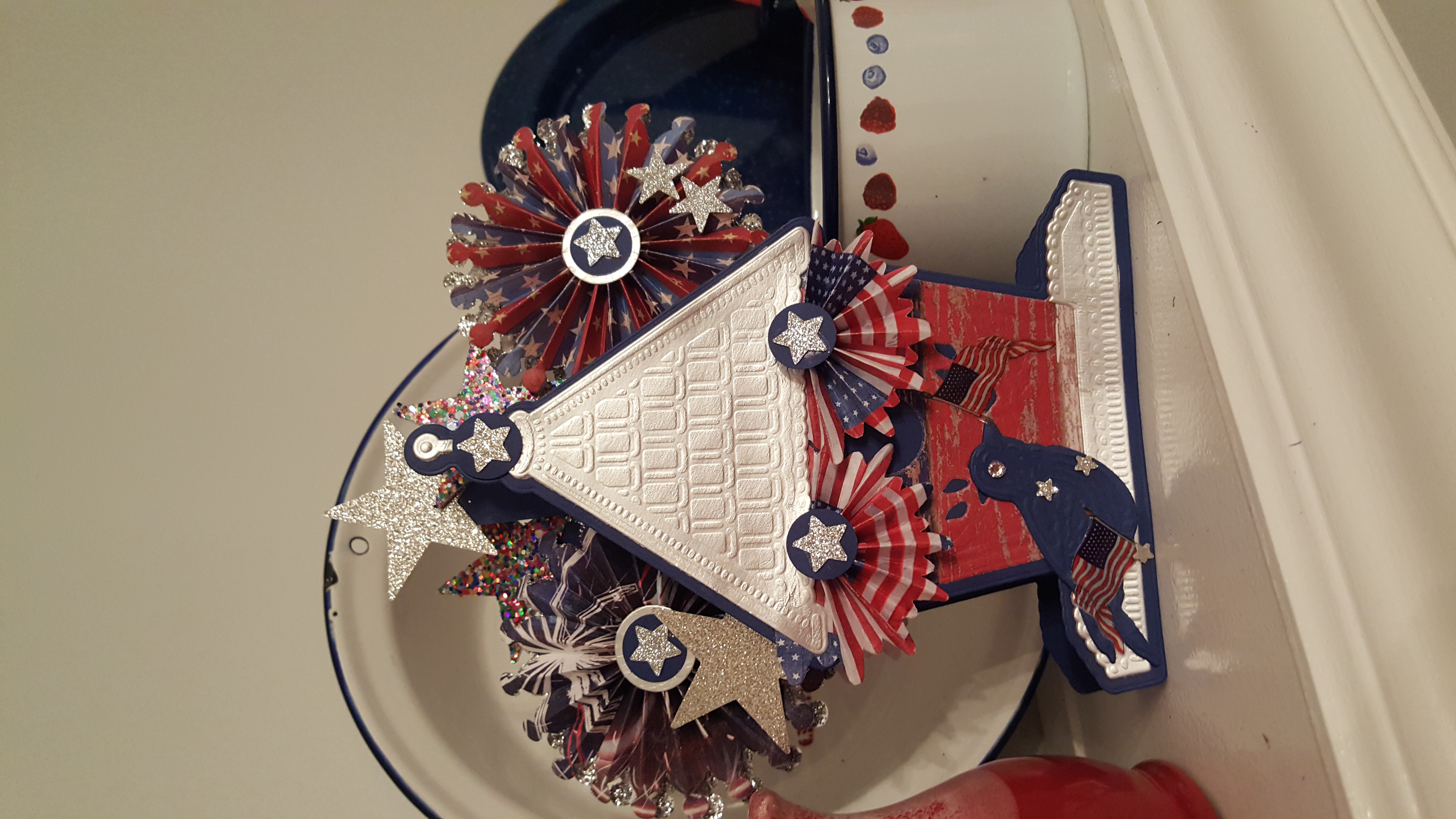 a red, white, and blue paper house on a shelf.