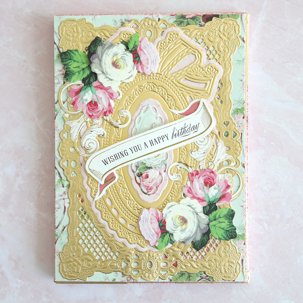 A pink and gold card with roses on it.