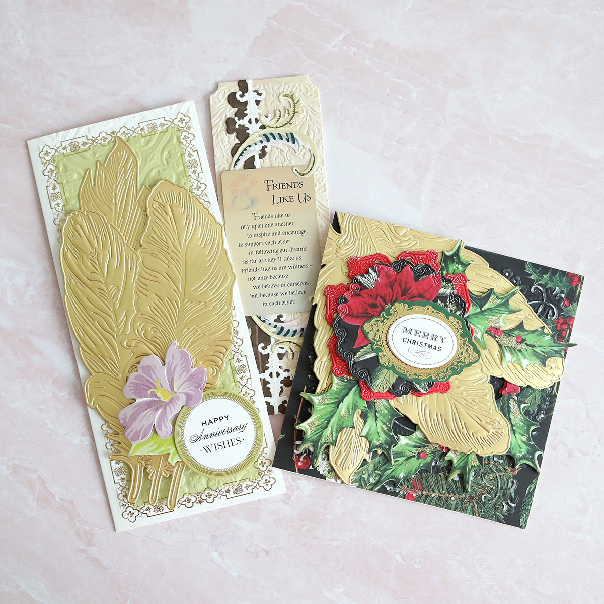 a set of christmas cards with a gold leaf and holly leaves.