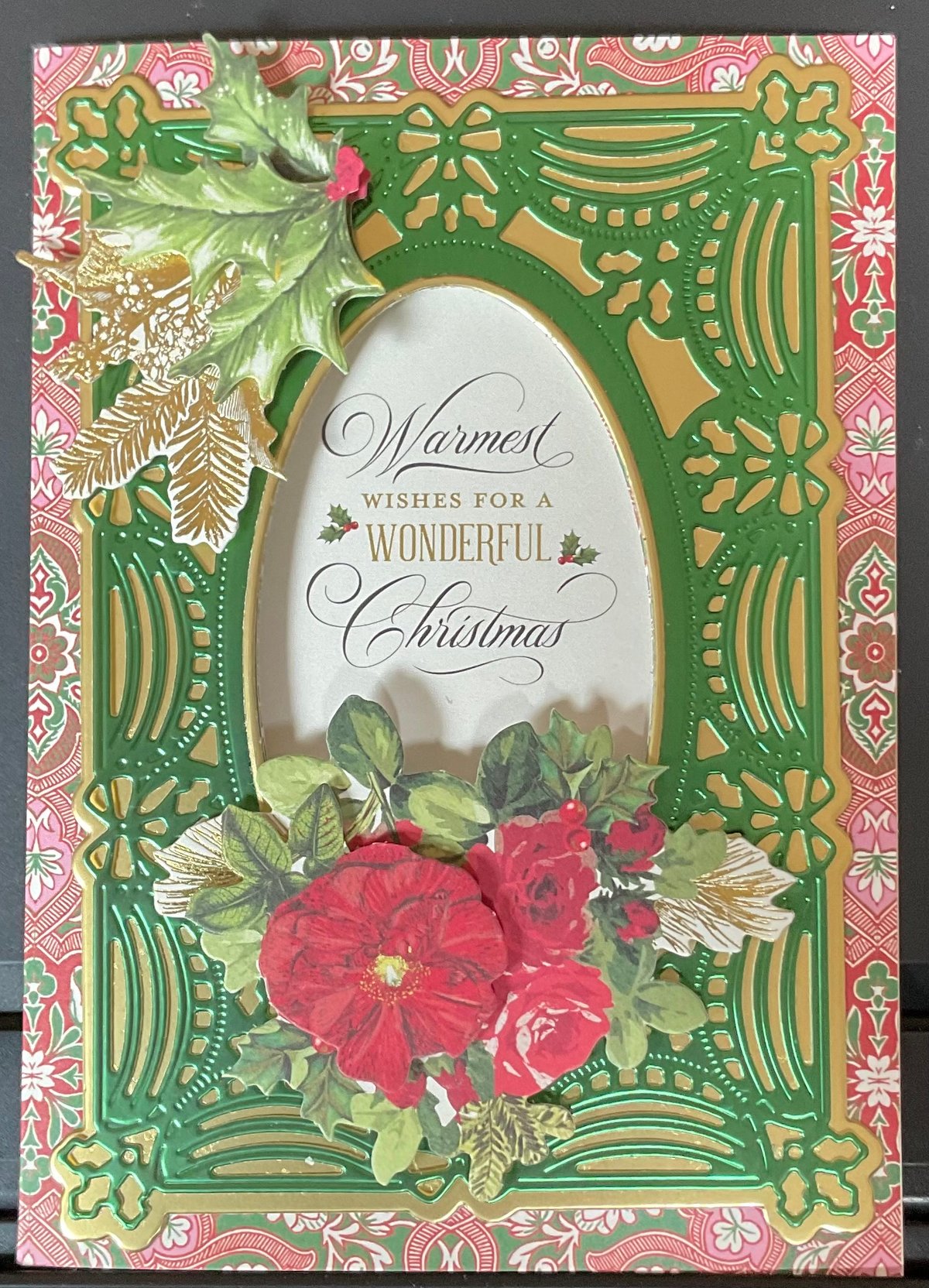 A christmas card with red roses and green leaves.