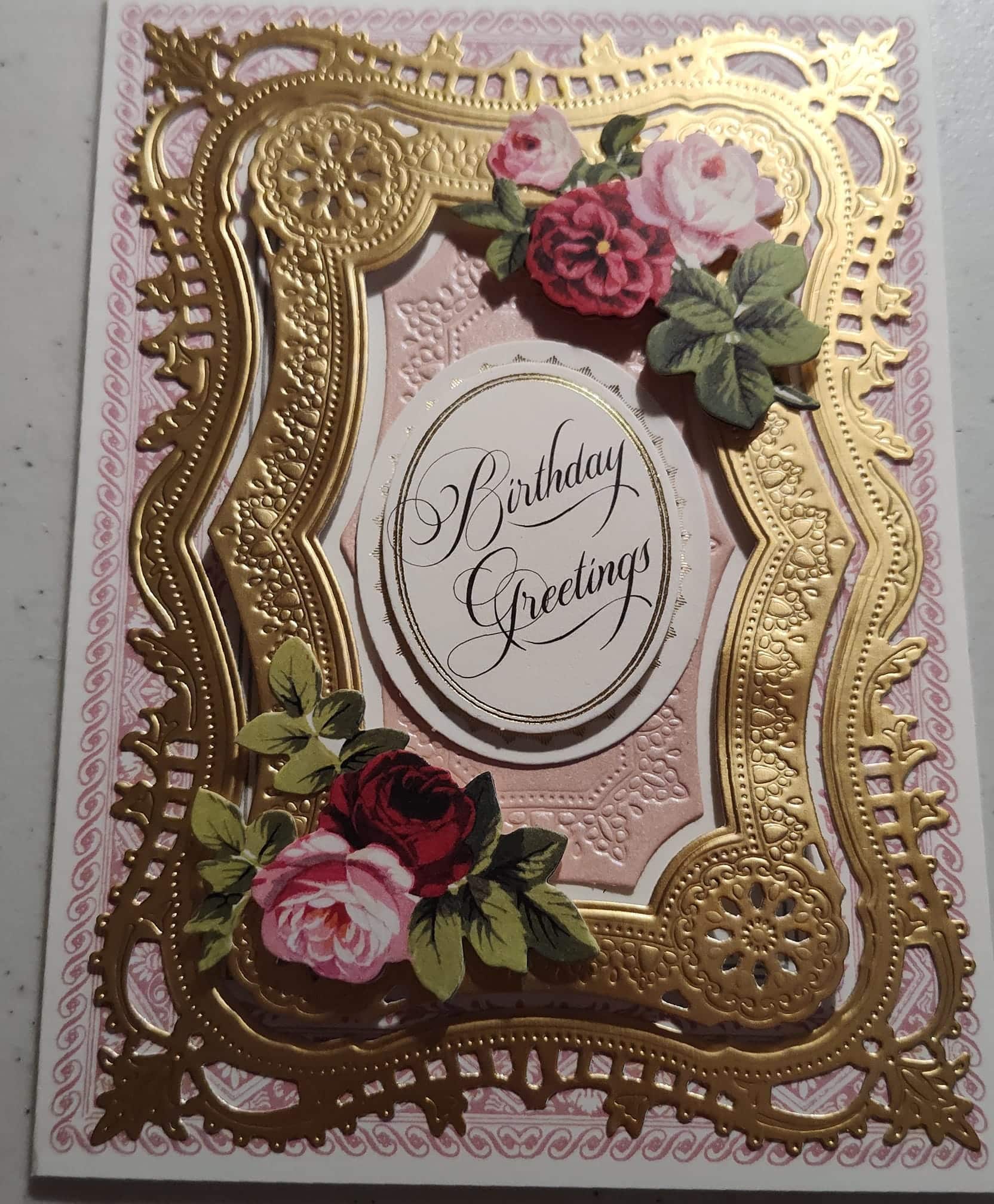 A pink and gold wedding card with roses.
