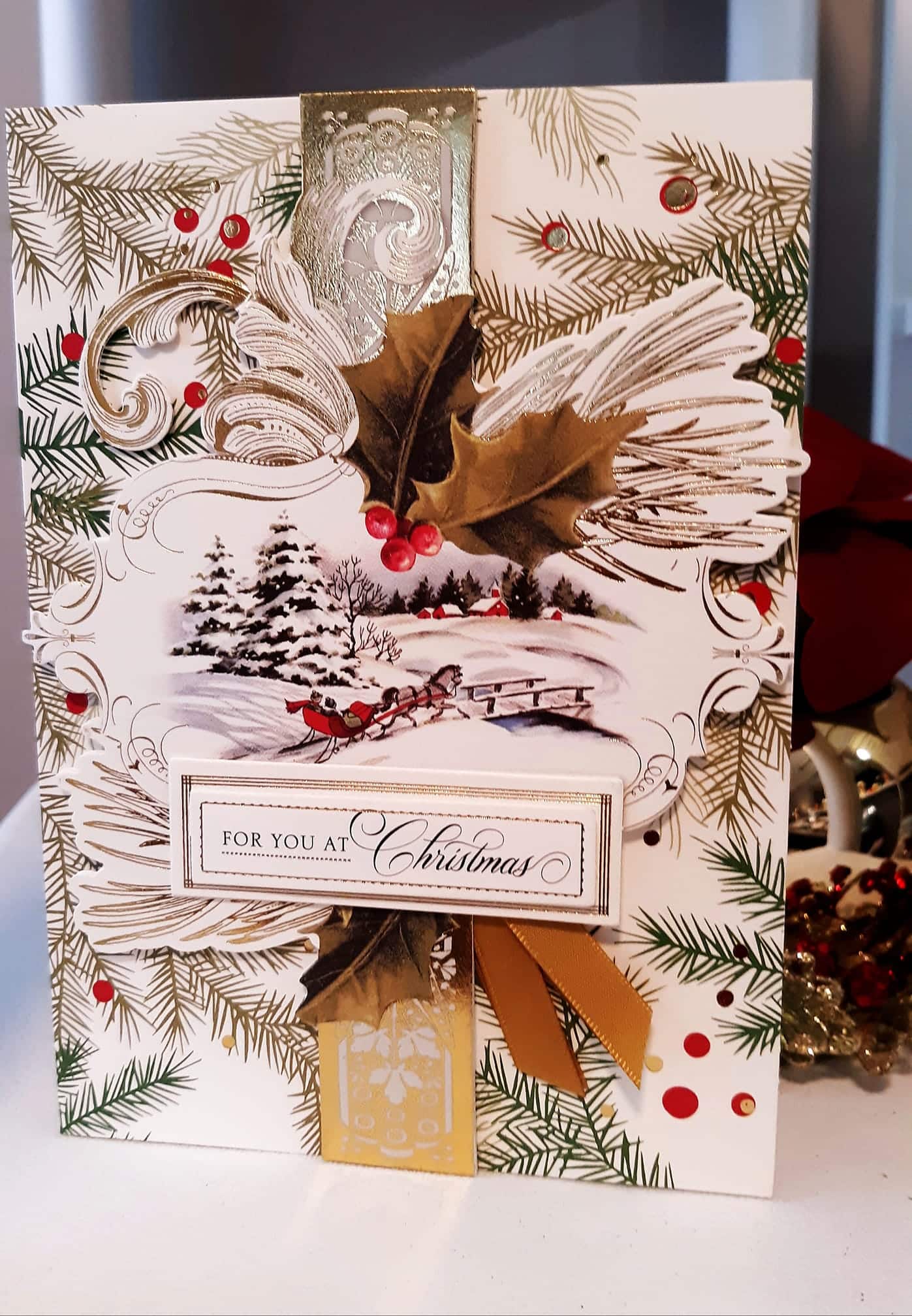 A christmas card with gold and silver decorations.