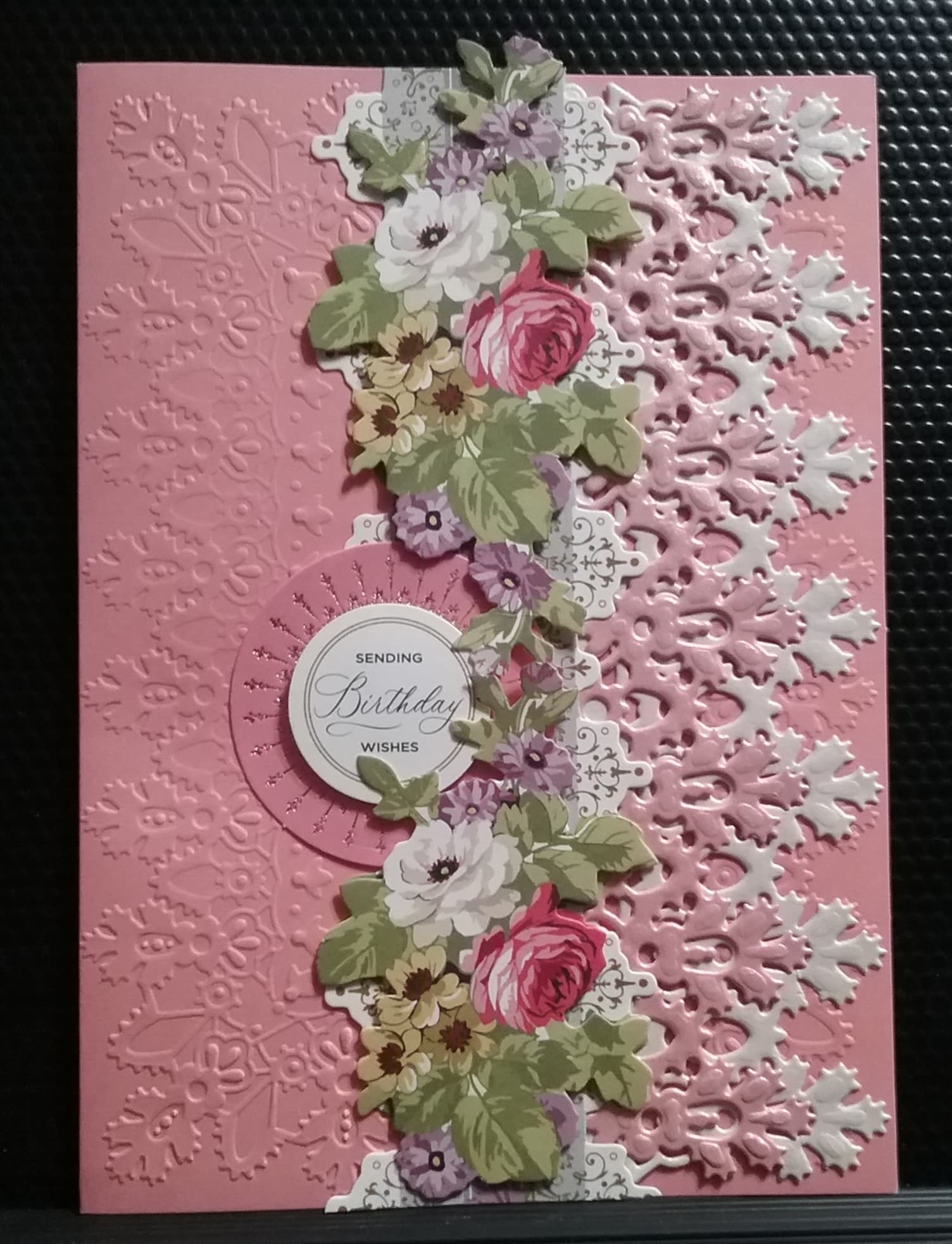 A pink card with lace and flowers.