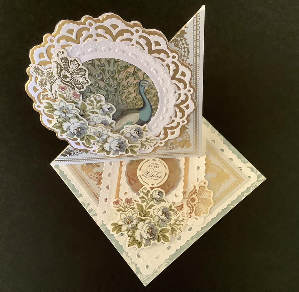 A gold and white card with a peacock on it.