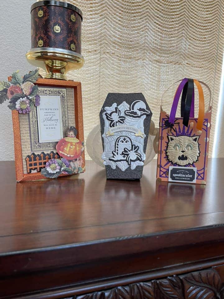 Three halloween decorations on a table next to a picture frame.