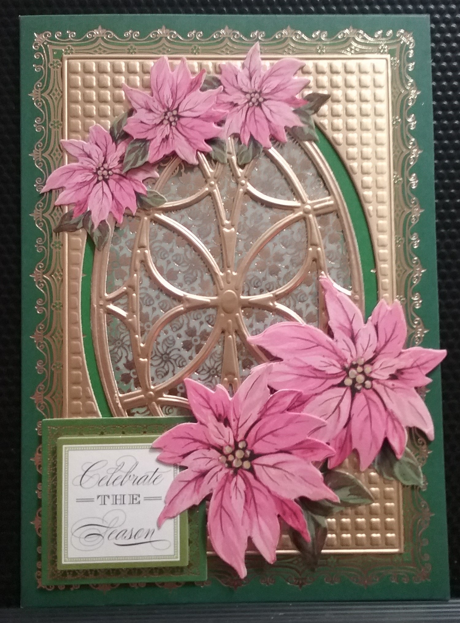 A card with pink poinsettias and a gold frame.