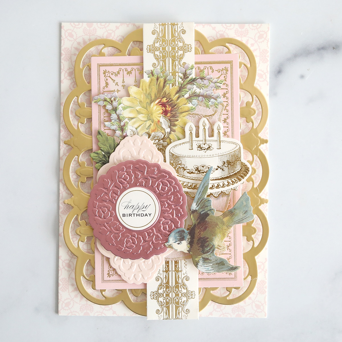 A pink and gold card with a bird and flowers.