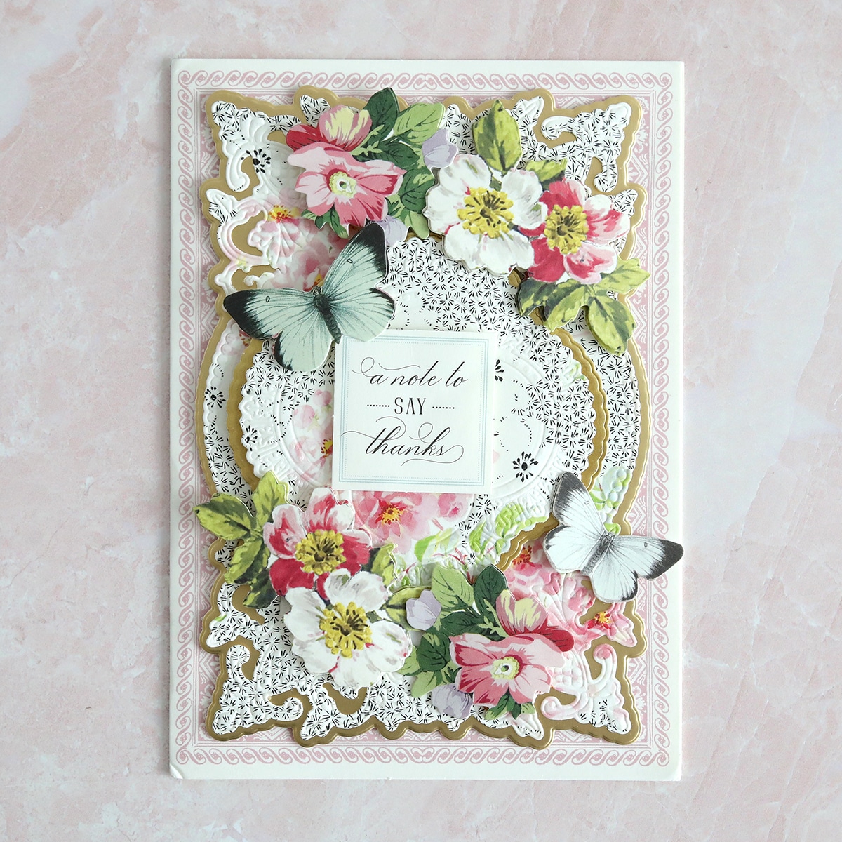 A card with flowers and butterflies on a pink background.