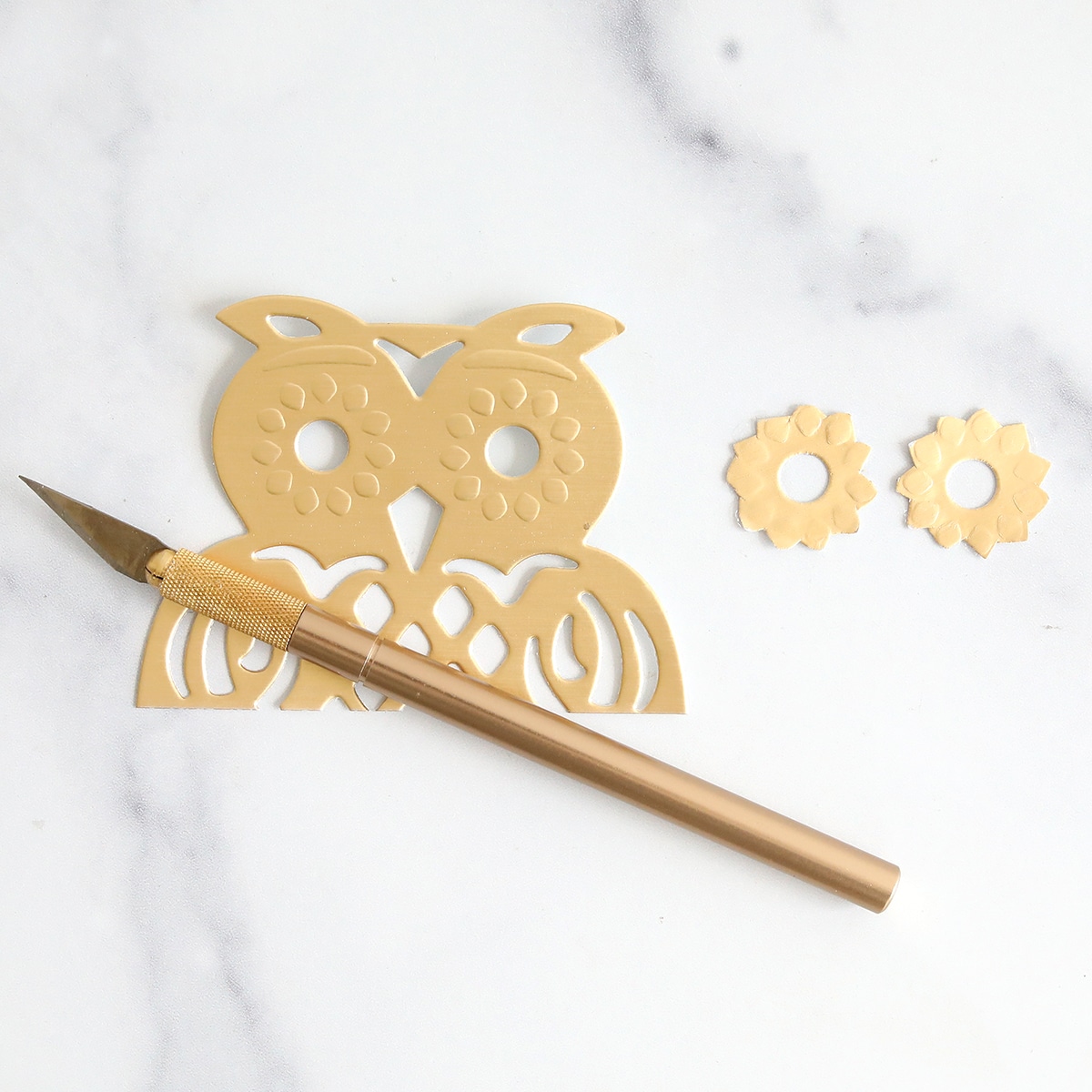 A gold owl and a pen on a marble table.