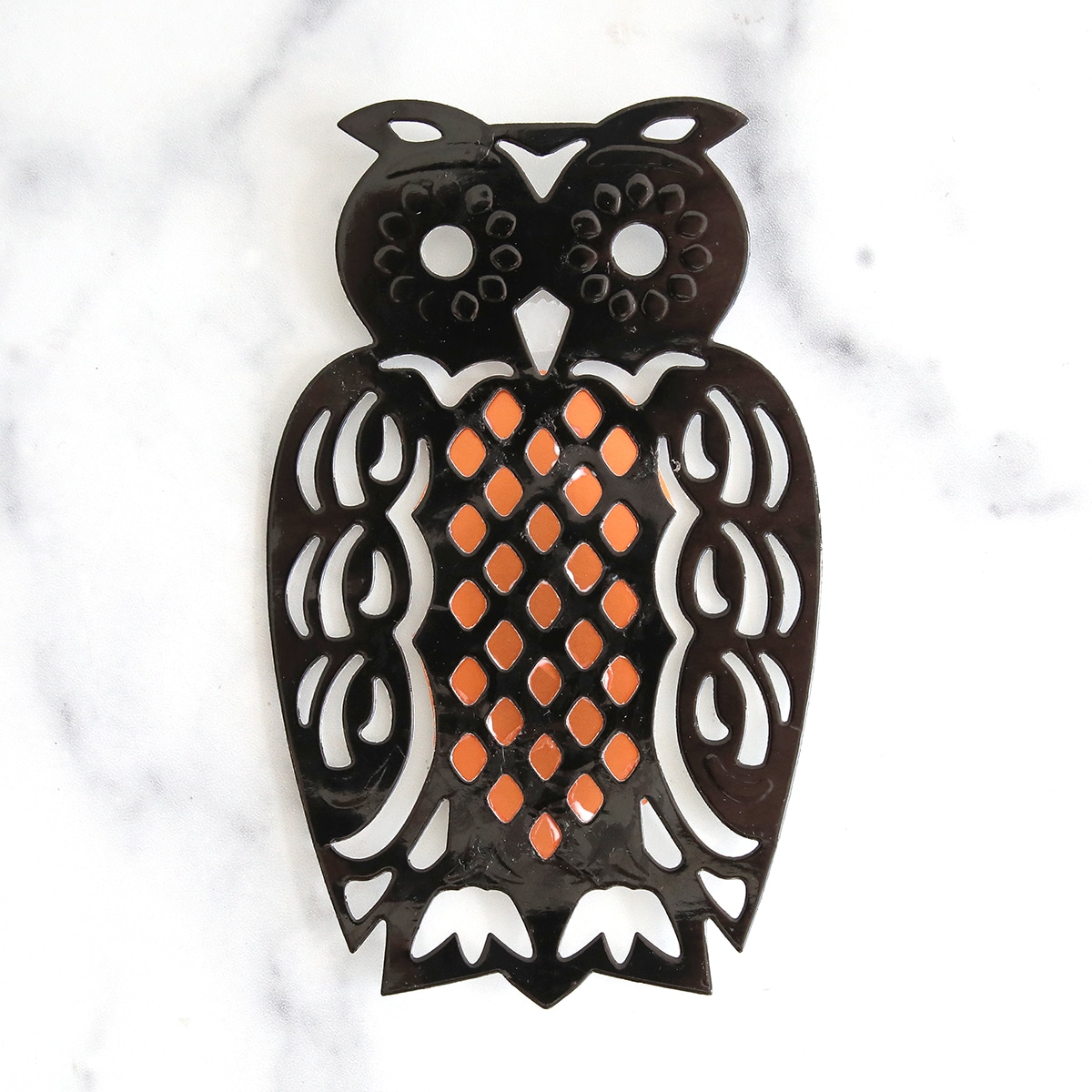 A black and orange owl on a marble countertop.