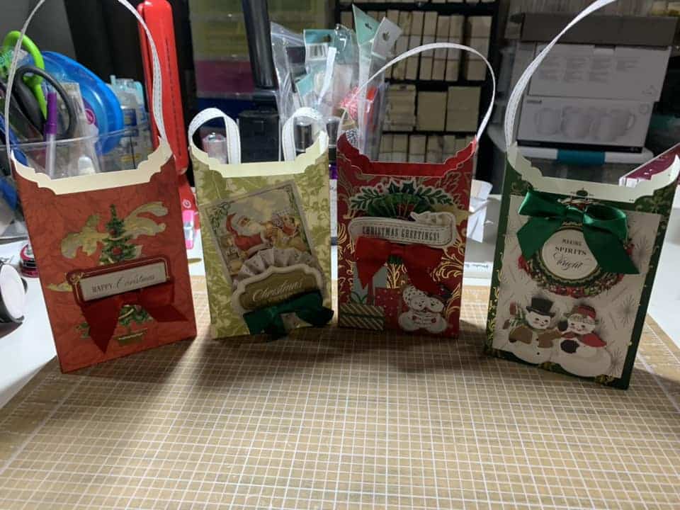 Three christmas gift bags sitting on a cutting board.