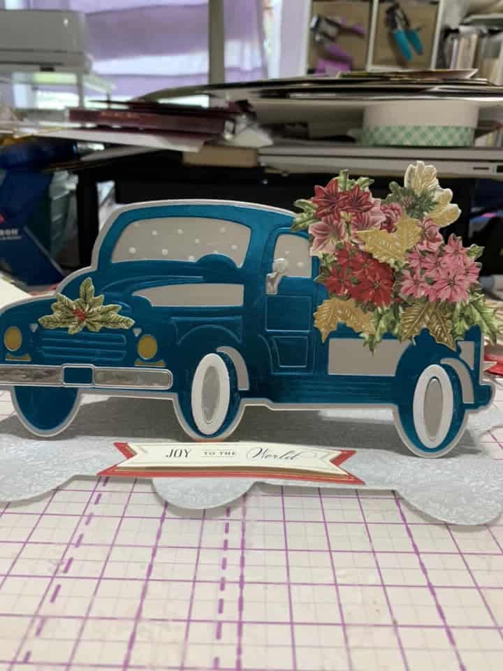 A card with a blue truck and flowers on it.