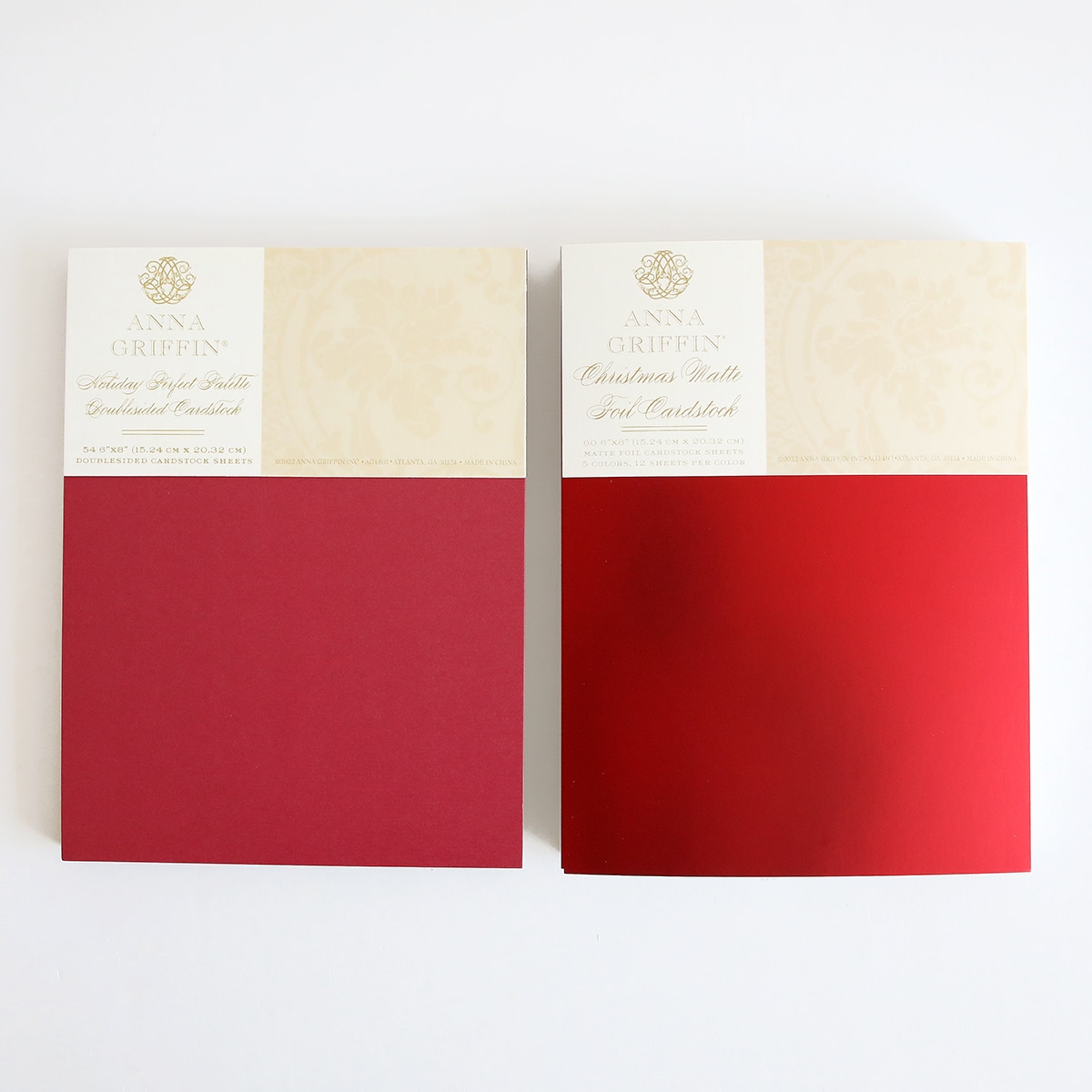Two red and white notebooks on a white surface.