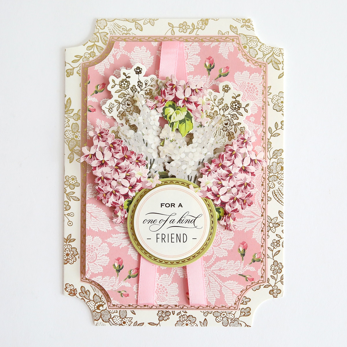 A pink and gold card with flowers on it.