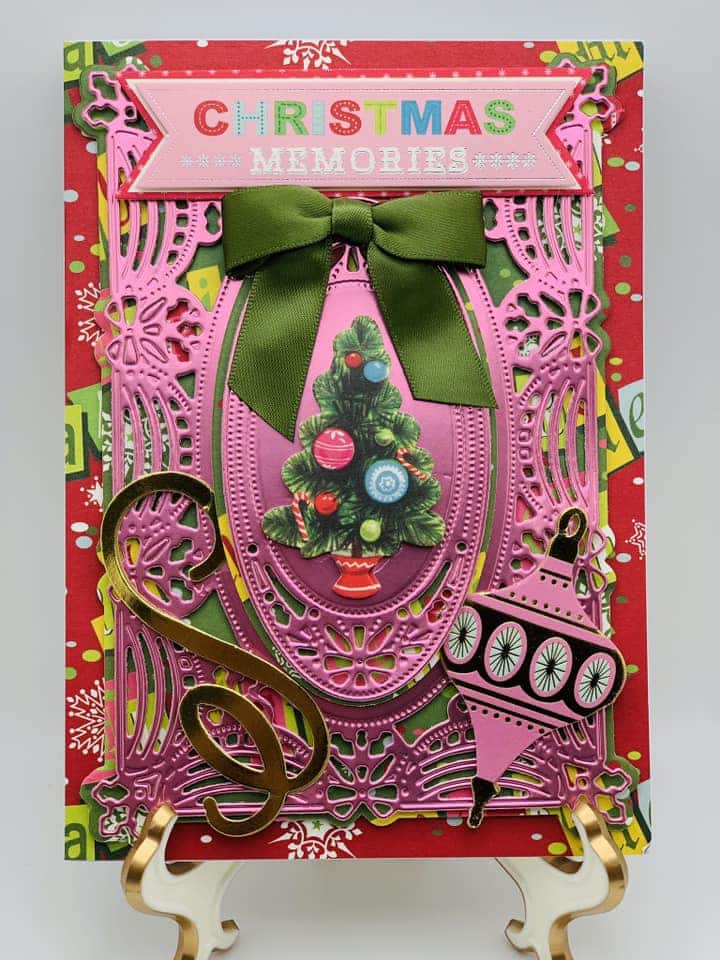 A christmas card with a pink tree and green ribbon.