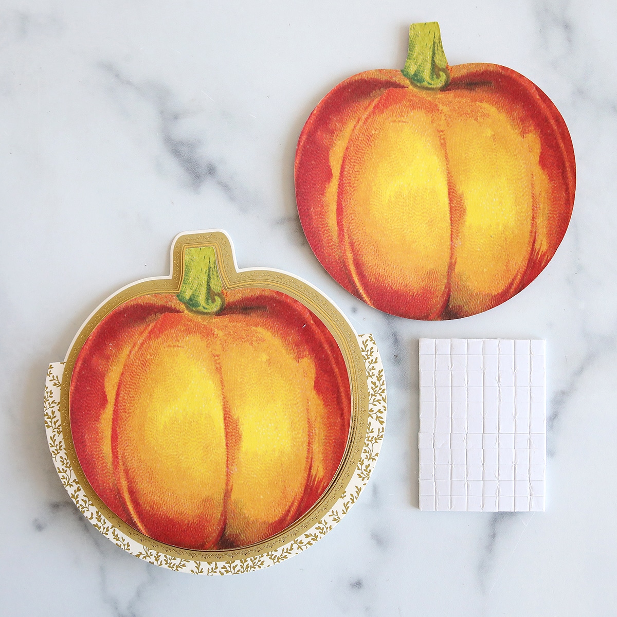 Two pumpkins and a notepad on a marble table.