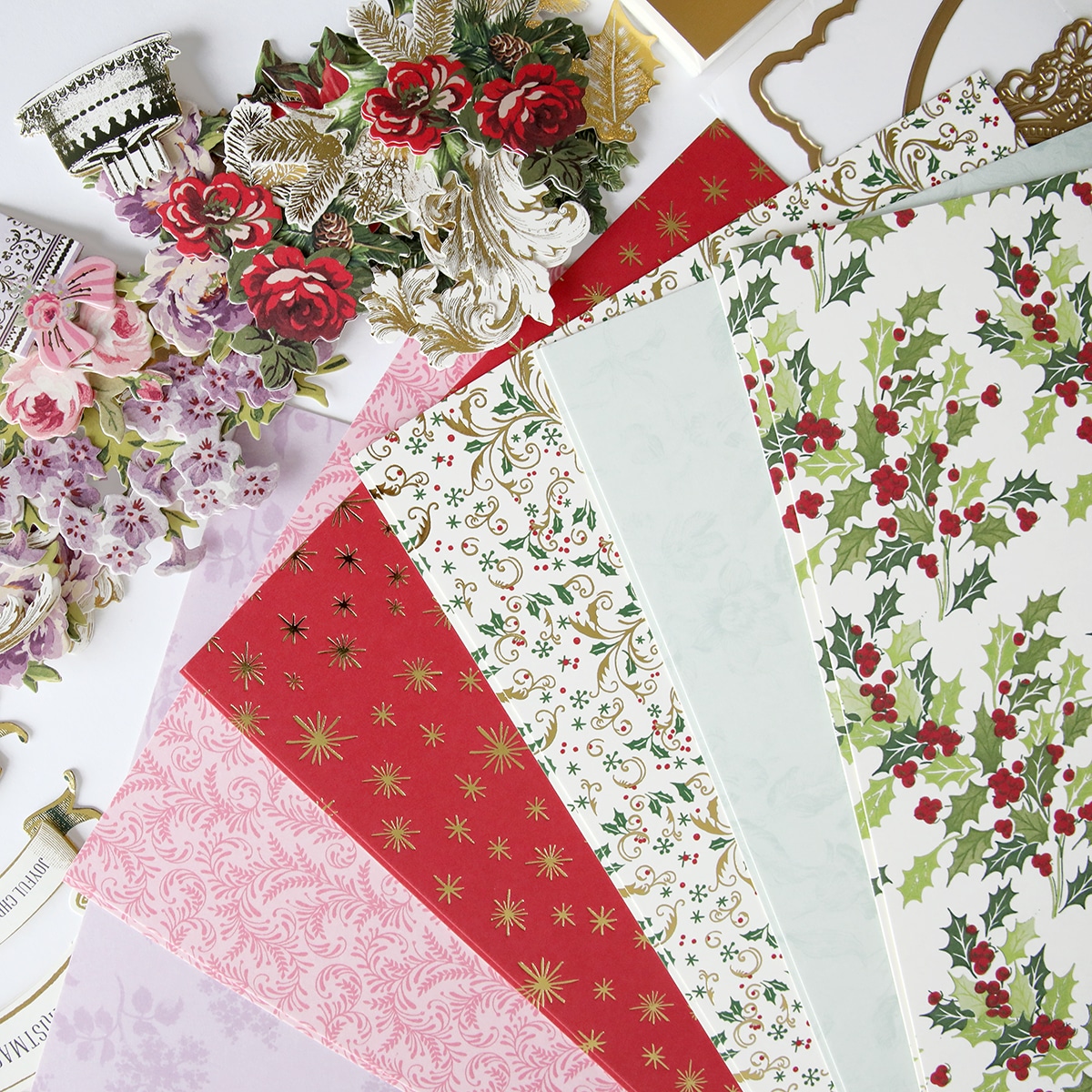 A variety of christmas papers and decorations are laid out on a table.