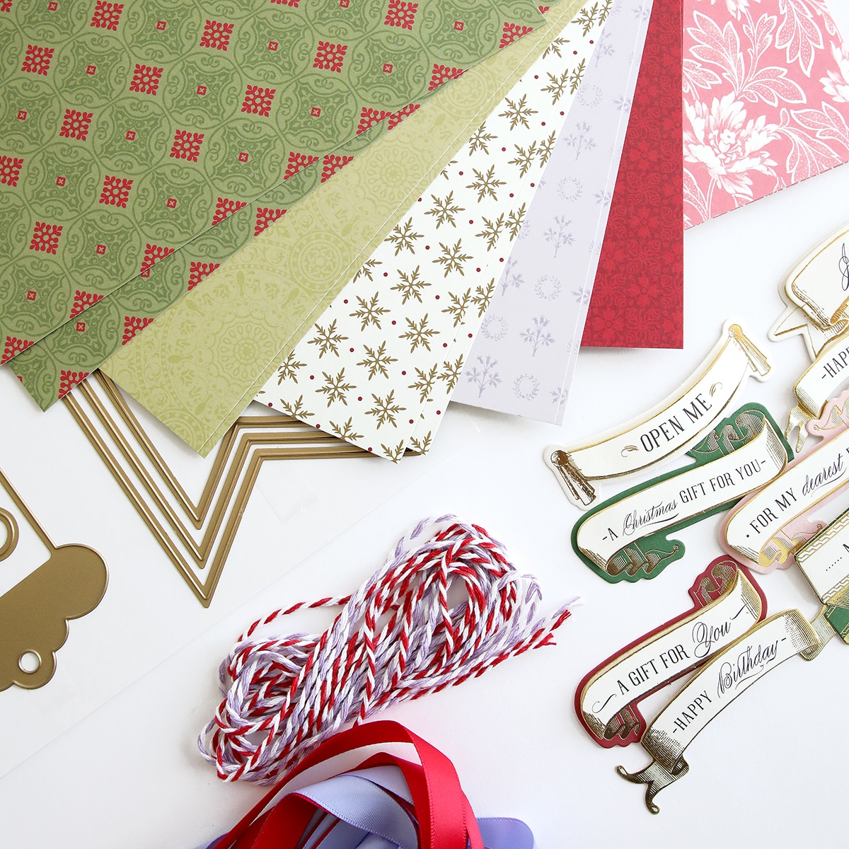 A variety of christmas papers and ribbons are laid out on a table.
