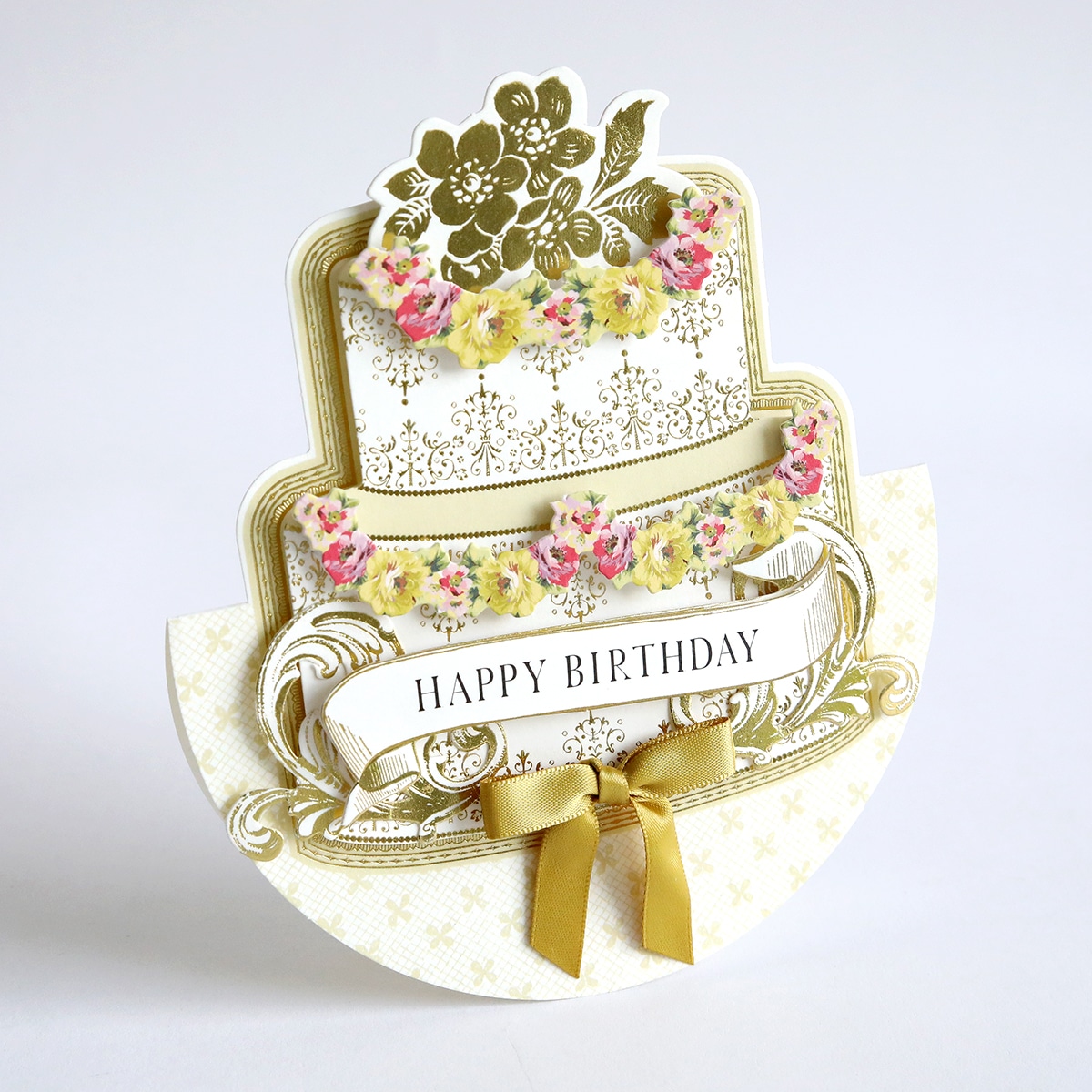 A happy birthday card with gold ribbon and flowers.