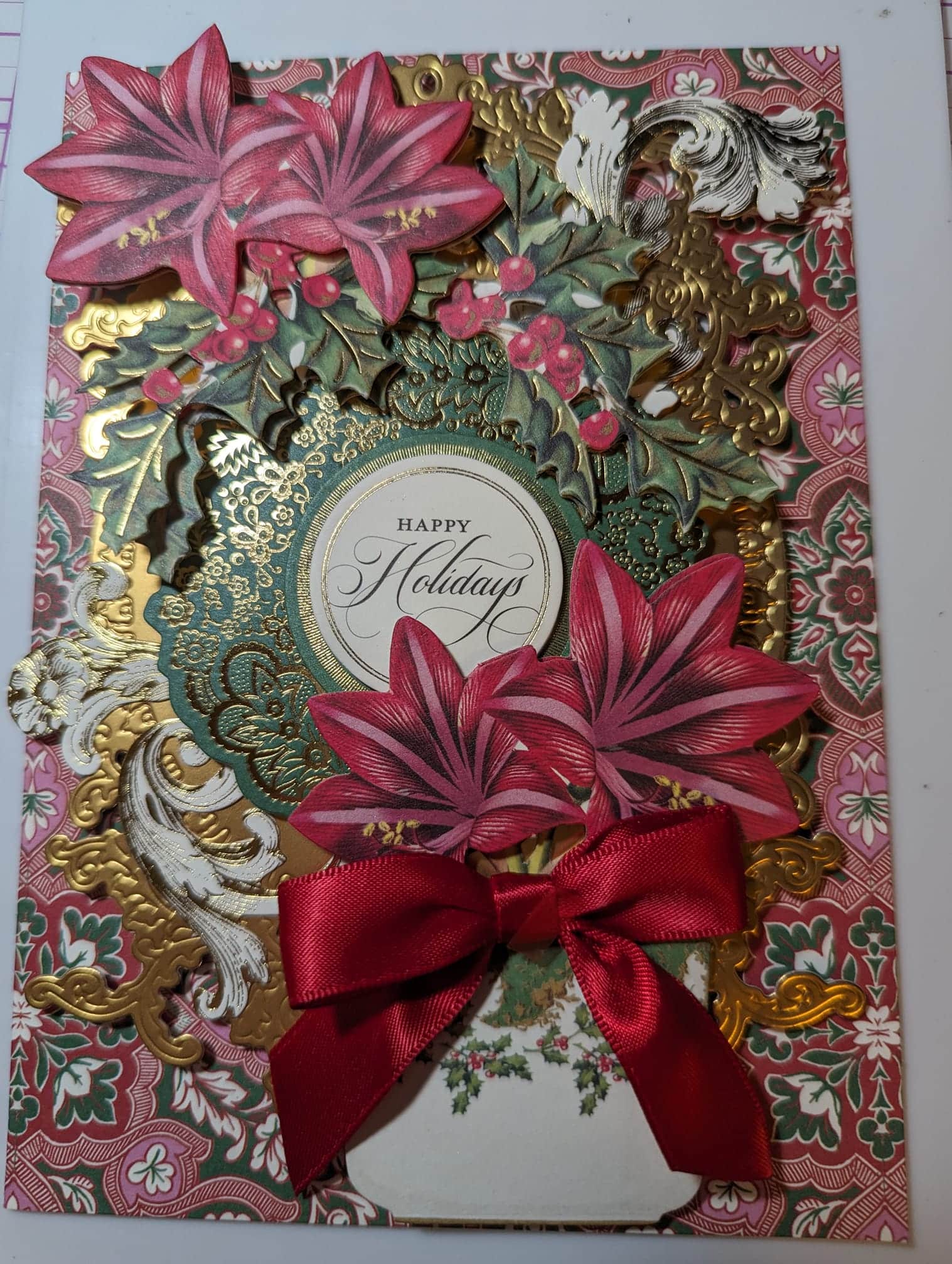 A holiday card with a bow and red flowers.