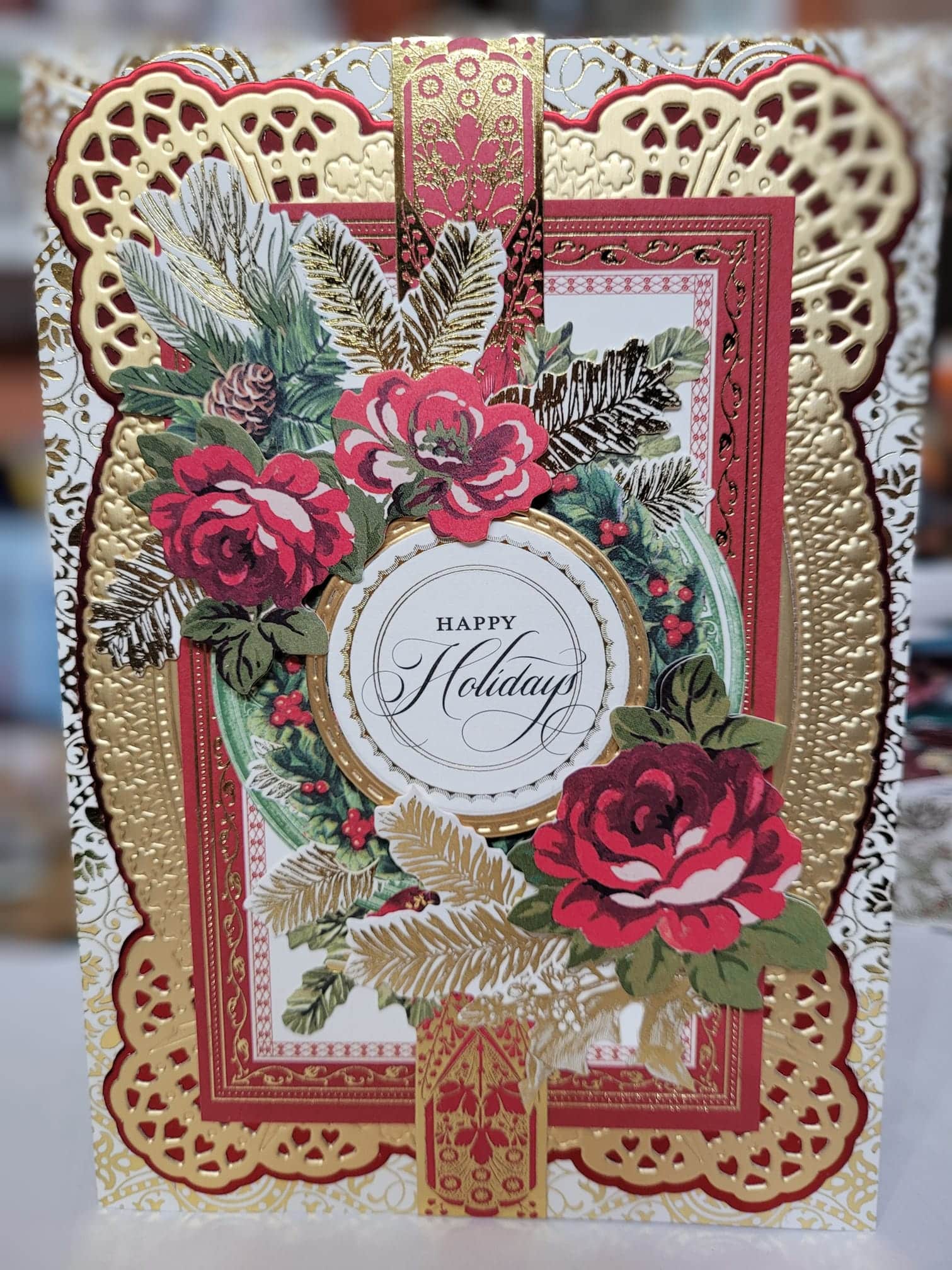 A christmas card with red roses and gold foil.