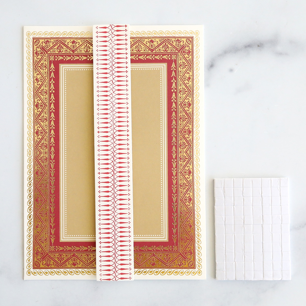 A card with a red and gold border and a piece of paper.