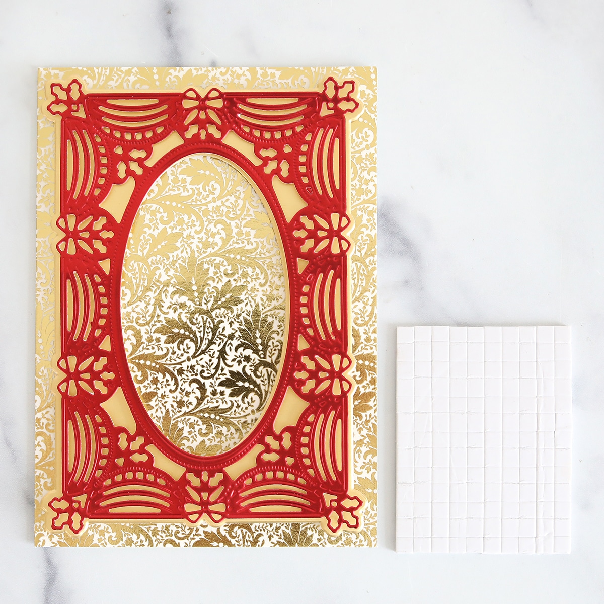 A card with a red and gold frame and a piece of paper.