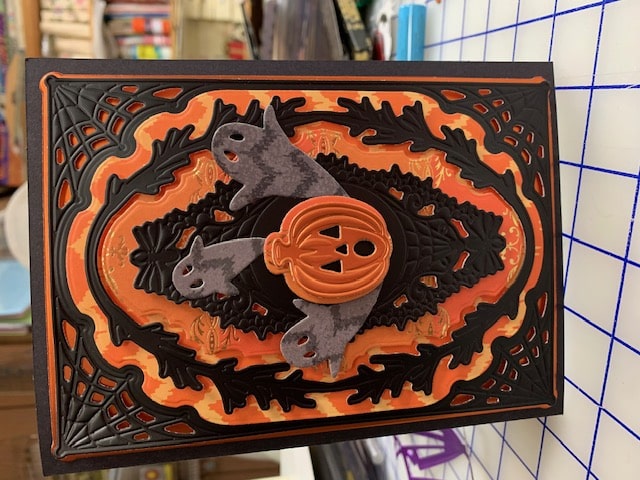 A black and orange halloween card with a bat on it.