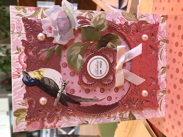A pink and white card with a bird on it.