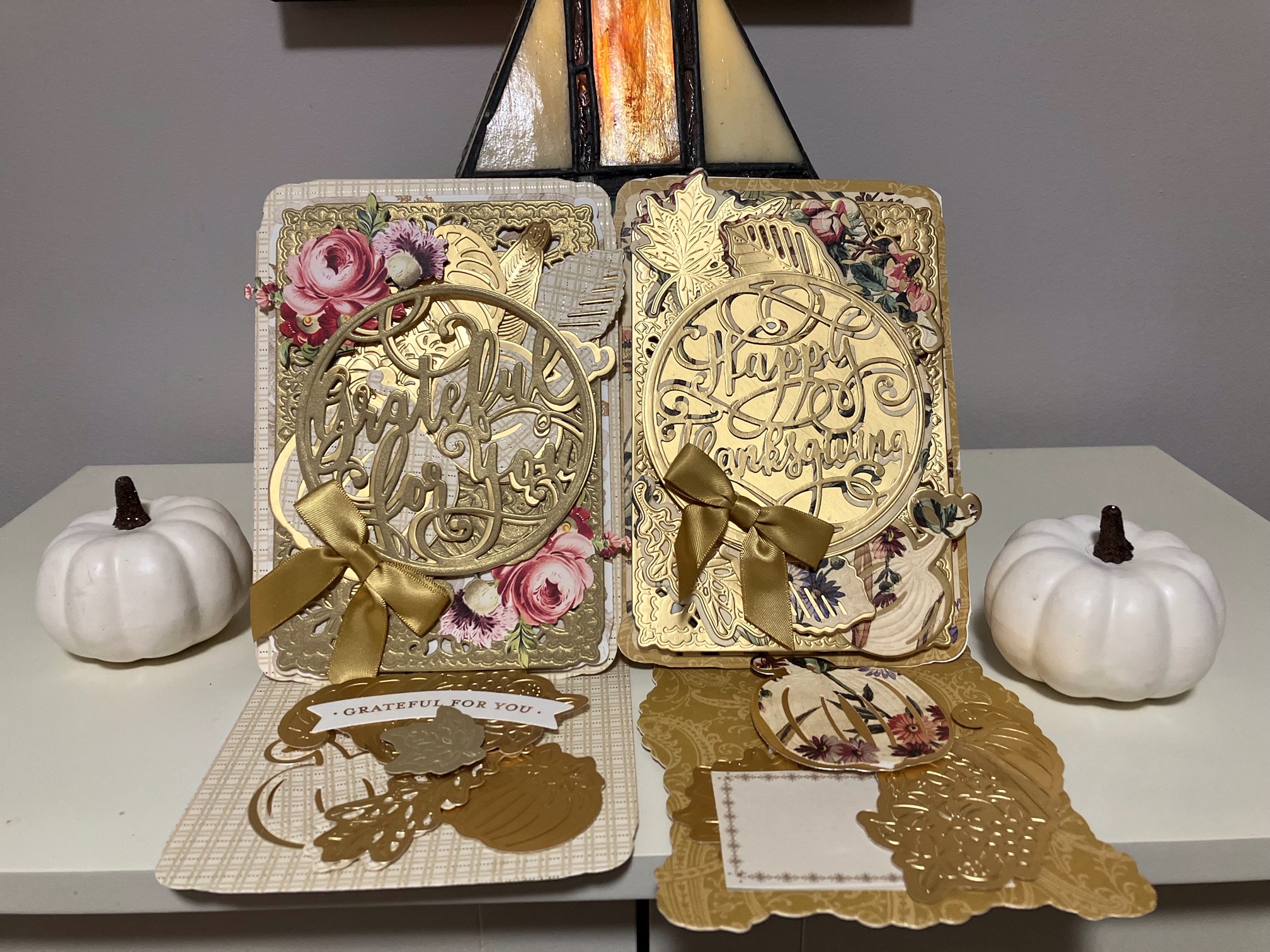 Two cards with gold foil and pumpkins on a table.